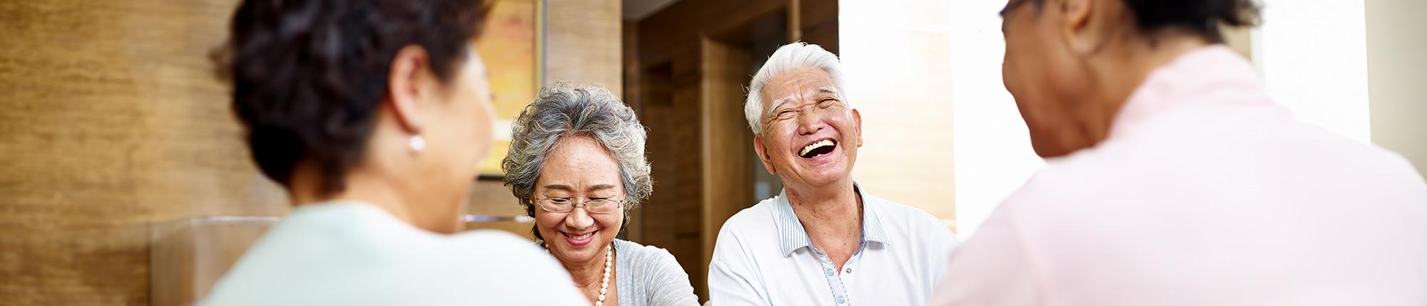 Four older people seated around a coffee table and smiling